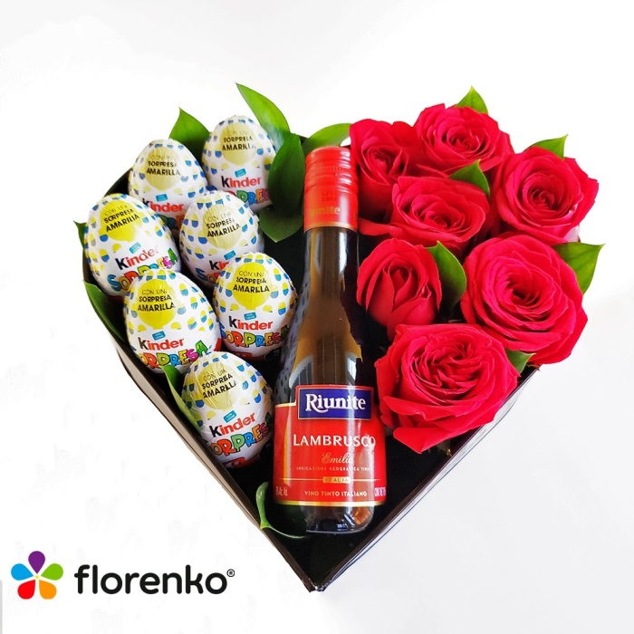 Corazón de rosas con chocolate y botella.