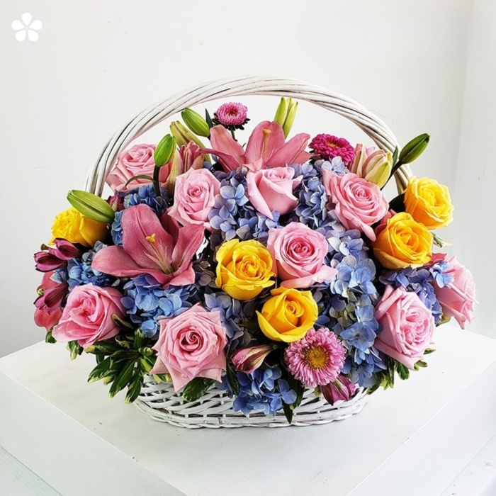 Canasta cubierta de rosas, lilis y hortensias