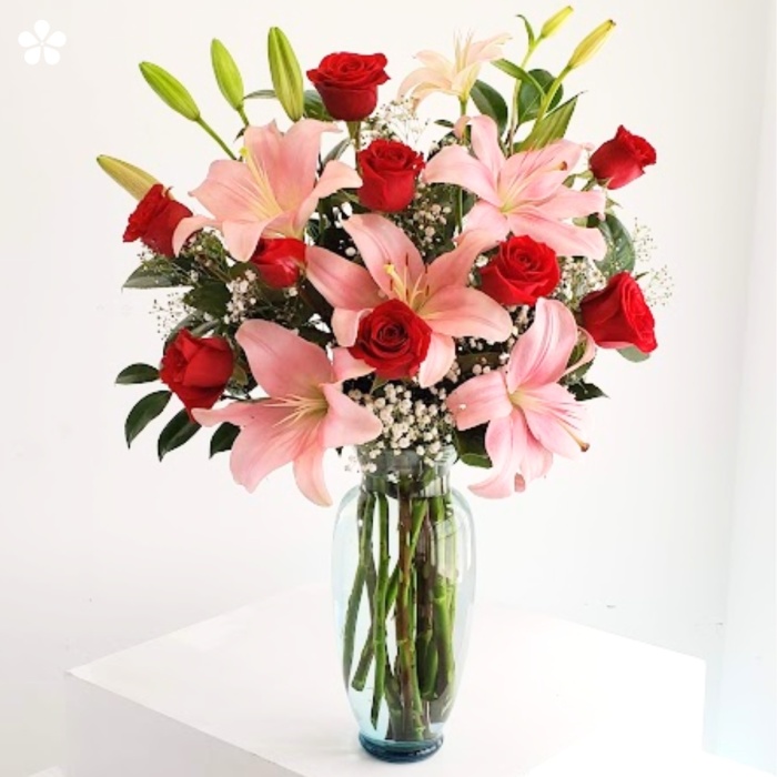 Florero de vidrio lleno de lilis y rosas