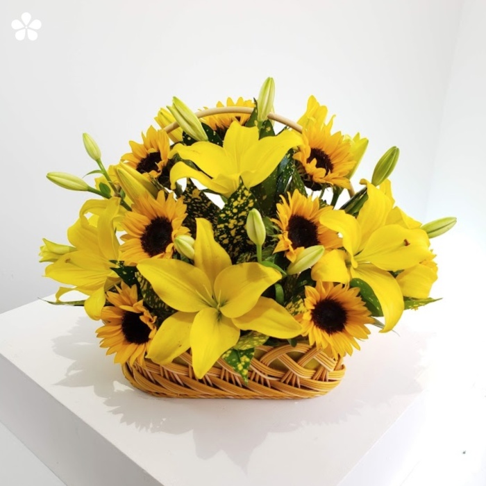 Girasoles y lilis en base de mimbre blanco