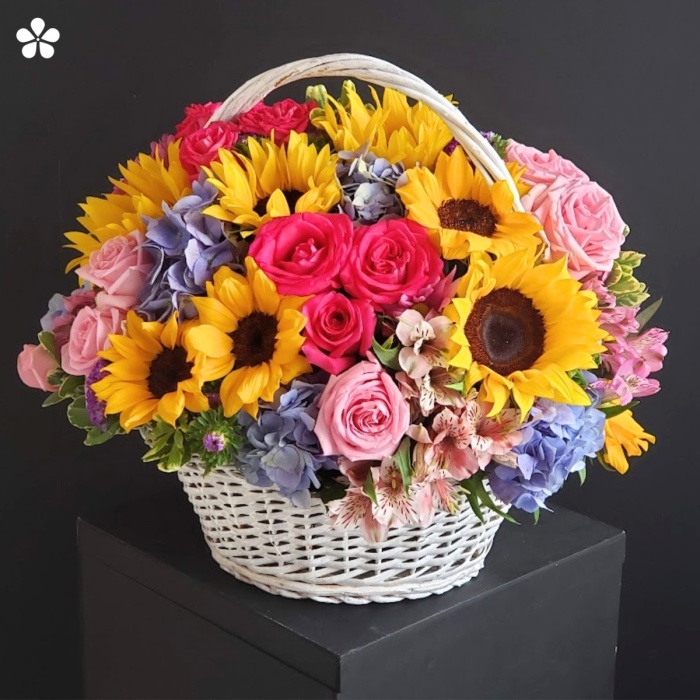 Girasoles, rosas, hortensias azules, astromelias en canasta vintage