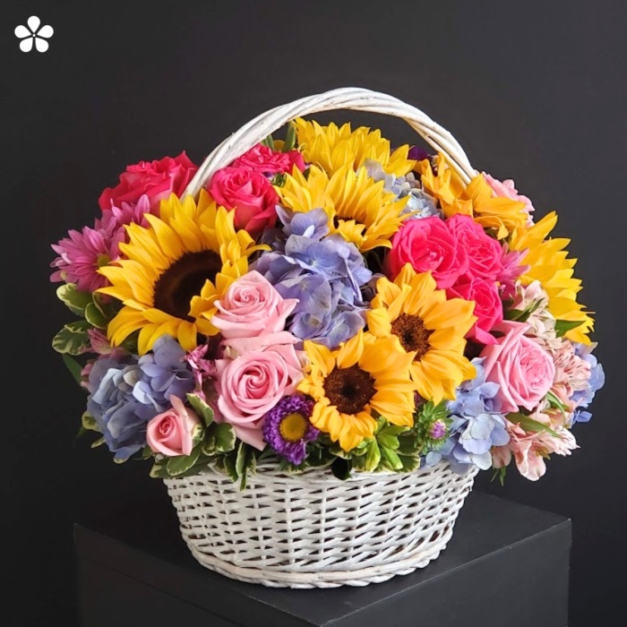 Girasoles, rosas, hortensias azules, astromelias en canasta vintage