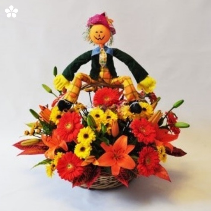 Muñeco de calabaza rodeado de lilis, gerberas y margaritas