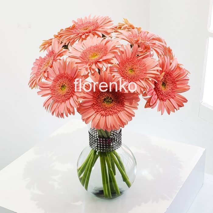 Gerberas salmón en florero de vidrio con corsé